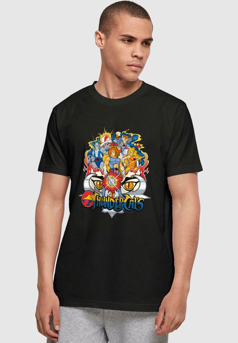Camiseta de algodón negra con un gráfico colorido de personajes de "Thundercats" con líneas marcadas y un logotipo prominente en la parte inferior.