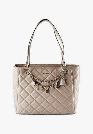 Sac fourre-tout matelassé beige avec doubles bretelles et chaînes dorées décoratives ornées de breloques incluant un cœur, une clé et une clochette.