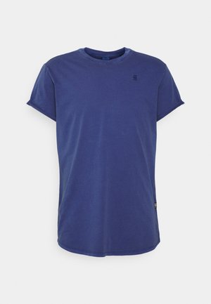 T-shirt uni bleu marine à manches courtes et col rond, avec un petit logo sur le côté gauche de la poitrine et une étiquette près de l'ourlet sur le côté droit.