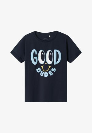 Camiseta de manga corta azul marino con el texto "GOOD DUDES" en azul claro y blanco, acompañada de un gráfico de una cara sonriente. Material de algodón.