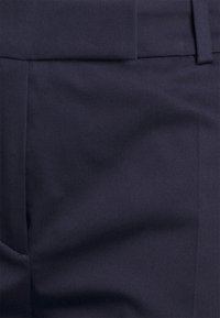 Granatowe spodnie o dopasowanym kroju, o gładkiej fakturze, z płaskim przodem i bocznymi kieszeniami, zaprojektowane w czystej, zorganizowanej sylwetce.