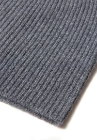 Tessuto grigio lavorato a maglia con una texture a coste, morbido e spesso, che presenta un colore uniforme e una leggera peluria lungo i bordi.