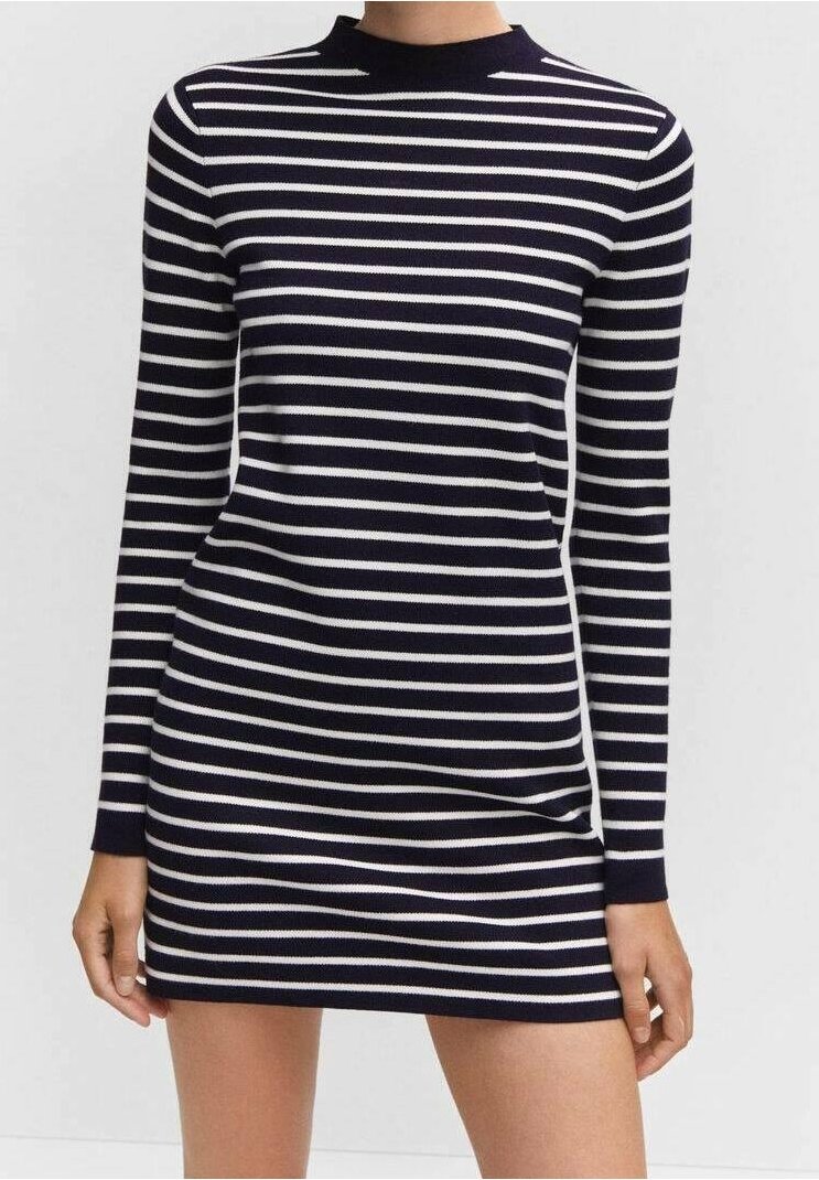 Femme portant une mini-robe moulante à manches longues, rayée horizontalement en noir et blanc, avec un col montant.