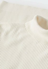Cremfarbener, gerippter Rollkragenpullover mit weichem Textil, der eine taillierte Passform und einen breiten Rippkragen aufweist. Glattes Material, minimale Details.