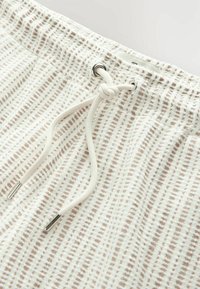 Gestructureerde, lichtbeige shorts met een trekkoord en taillestrik, voorzien van een geweven patroon en metalen oogjes als accenten.