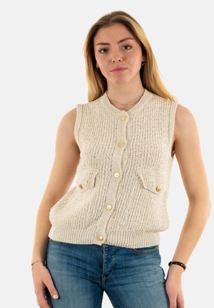 Gebreide mouwloze vest in crème kleur, met een textuurpatroon, vier voorzakken en een ronde hals met gouden knopen.