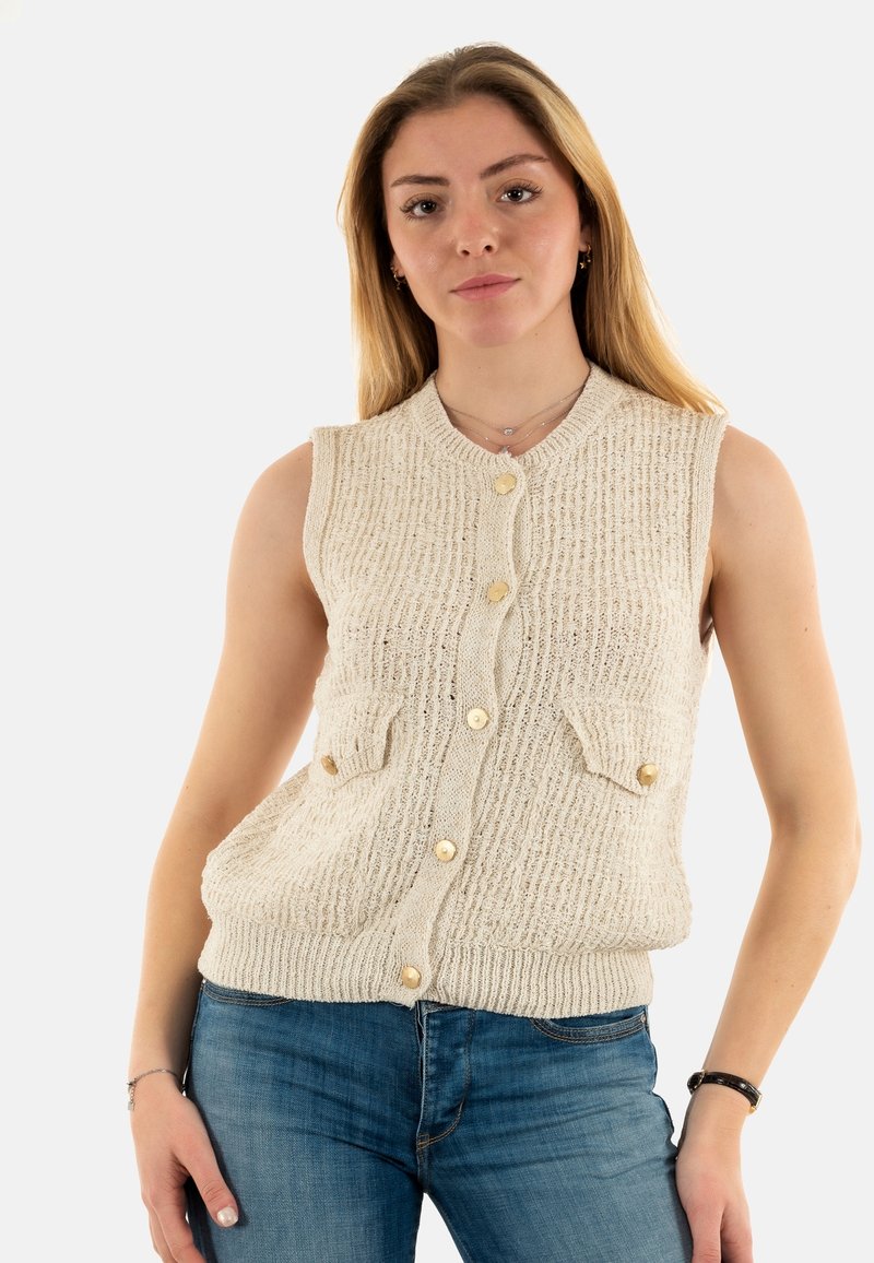 Chaleco sin mangas de punto en color crema, con un patrón texturizado, cuatro bolsillos frontales y un escote redondo con botones dorados.