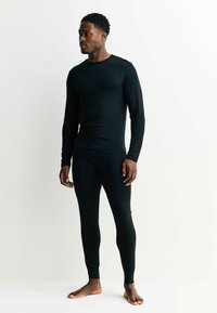 Fekete hosszú ujjú felső és testhezálló nadrágok sima anyagból, egyszerű dizájnnal és kerek nyakkivágással.