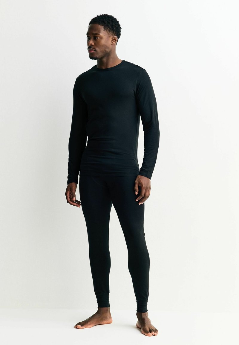 Fekete hosszú ujjú felső és testhezálló nadrágok sima anyagból, egyszerű dizájnnal és kerek nyakkivágással.