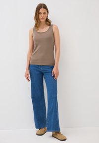 Top sin mangas color marrón combinado con jeans de pierna ancha azules y calzado marrón. El top tiene una textura suave y un escote redondeado.