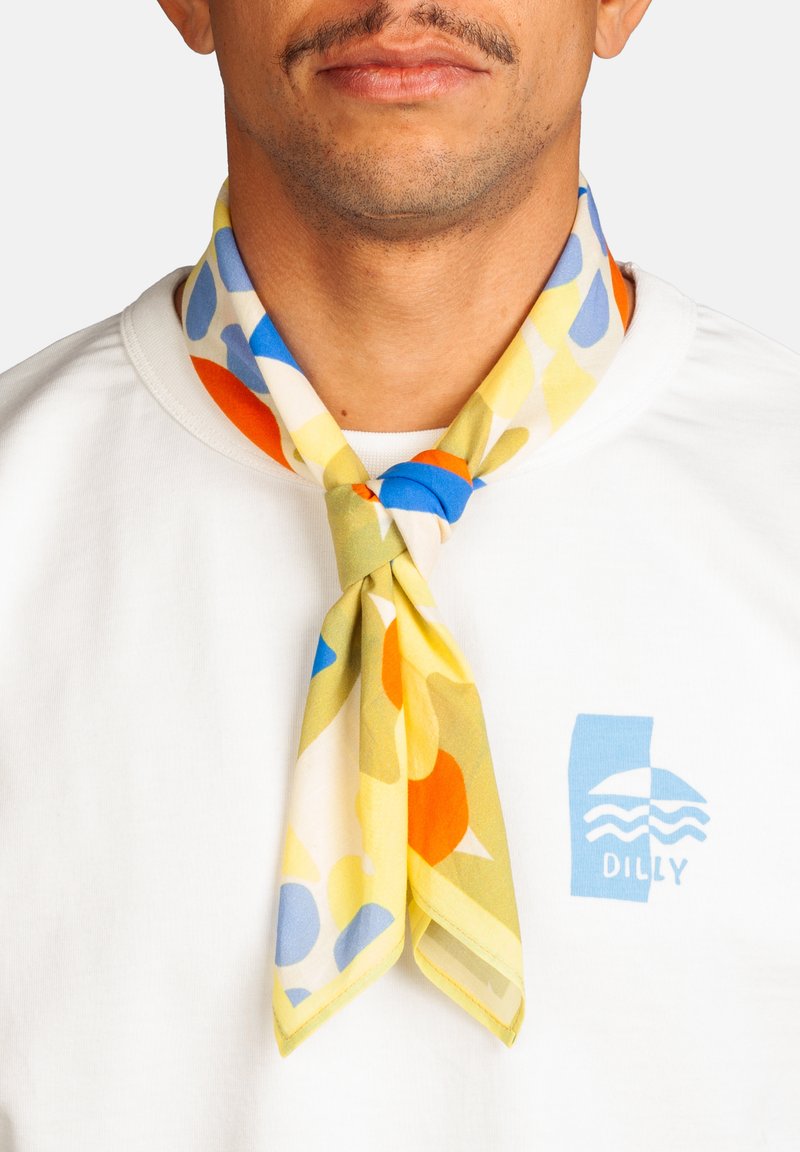 Homme portant une chemise blanche avec le logo "Dilly" bleu et une écharpe colorée aux motifs abstraits bleus, jaunes, oranges et verts nouée autour du cou.