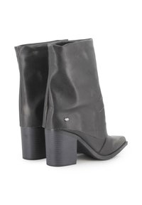 Botas de tobillo de cuero negro con un diseño suelto, puntera redondeada y un tacón de bloque texturizado. Presentan costuras sutiles y un pequeño acento metálico.