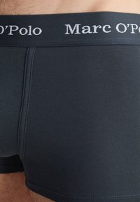 Mörkblå bomullboxerbriefs med mjuk textur, med en vit logotyp på den elastiska midjebandet och minimala sömmande detaljer.