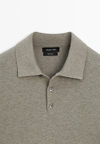 Hellgraues Baumwoll-Poloshirt mit zwei Knöpfen und umgelegtem Kragen, mit dem Etikett Massimo Dutti, hergestellt in China.