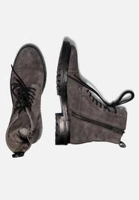 Bottes cheville en daim gris avec une finition texturée, dotées de lacets noirs, d'une fermeture éclair latérale et d'une semelle en caoutchouc épaisse.