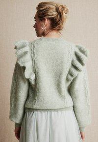 Miętowa sweter dziany z falbaniastymi rękawami, teksturą w warkocze i miękkim, puszystym wykończeniem. Obniżony tylny brzeg.
