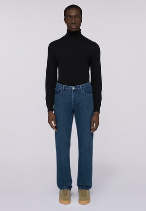Black turtleneck sweater, blue jeans, and beige high-top sneakers. Straight-leg jeans with standard pockets and light blue stitching.