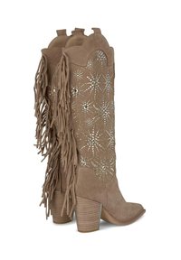 Botas de ante color marrón claro hasta la rodilla con detalles de flecos, adornadas con tachuelas metálicas y un diseño superior con forma de onda, con un tacón grueso.