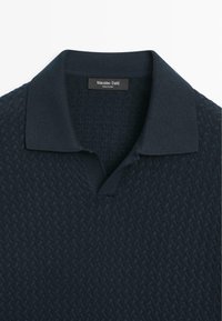 Polo en maille bleu marine foncé avec motif texturé et col ouvert, étiquette Massimo Dutti, fabriqué en Chine.
