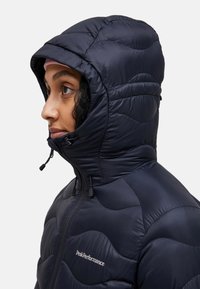 Navy puffer jacket with a zip-up front and hood, featuring quilted texture, elastic toggles, and a logo on the chest. Smooth, shiny material.