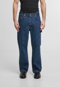 Zili denim stila bikses ar brīvu griezumu, kurām ir sānu kabatas, pogu un rāvējslēdzēja aizdare, kā arī gluda, izturīga tekstūra.