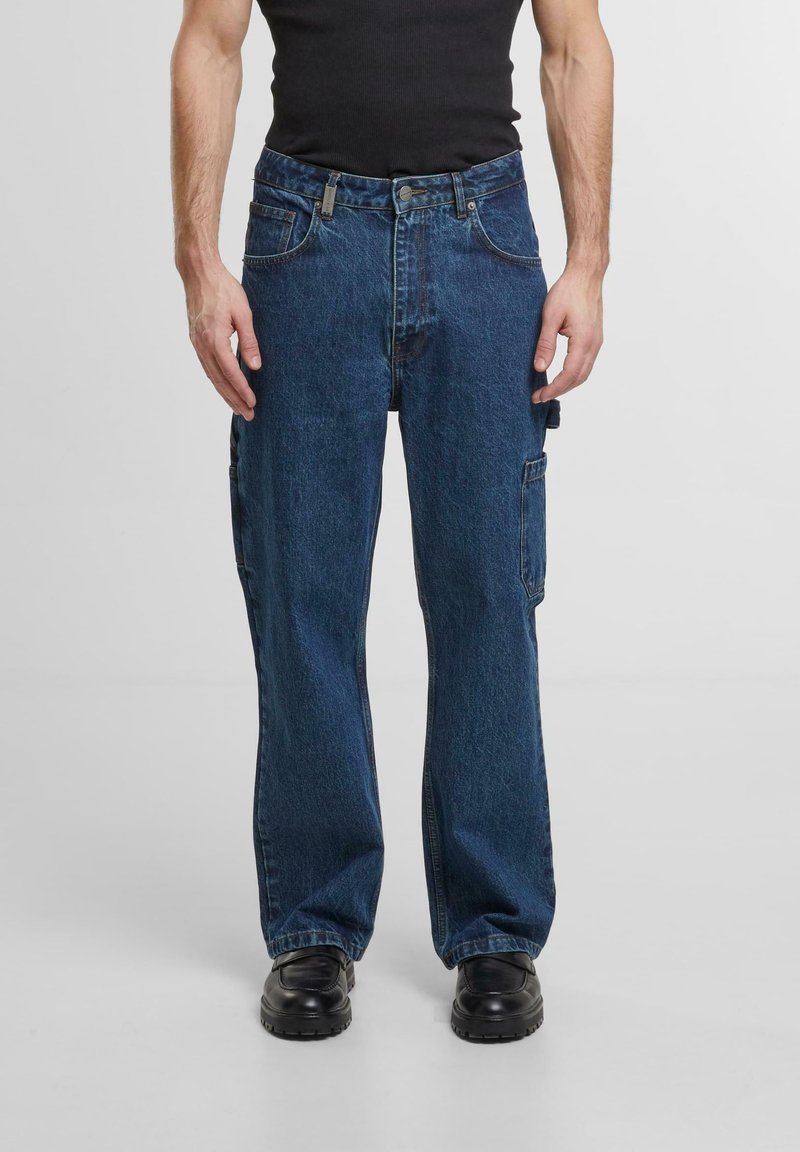 Zili denim stila bikses ar brīvu griezumu, kurām ir sānu kabatas, pogu un rāvējslēdzēja aizdare, kā arī gluda, izturīga tekstūra.