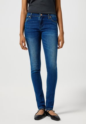 Jean skinny bleus avec un lavage moyen, design à cinq poches et couture classique. La taille présente un bouton en métal et un délavage subtil.