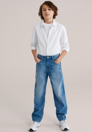 Sinised teksad lõdva istumisega, millel on kõrge vöökoht, hele pleekimine ja viis taskut. Ühitatud valge nööbitava särgiga.