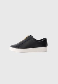Svart lavt lær sneakers med hvit såle og gullglidelås, sidevisning, minimalistisk stil på ensfarget bakgrunn.