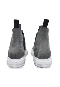 Botas de tobillo de ante gris con paneles elásticos en los laterales, suela de goma blanca y tiradores traseros. Presentan un diseño elegante y moderno.