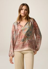 Bluză catifelată cu decolteu în V și mâneci lungi, cu un model floral în nuanțe de roz, albastru și aurie. Baza rotundă, croi lejer.