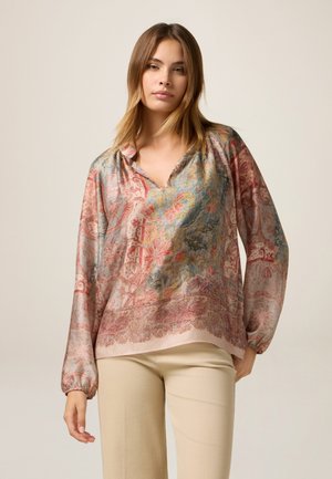 Blusa di seta con scollatura a V e maniche lunghe, caratterizzata da un motivo floreale nelle tonalità di rosa, blu e oro. Orlo arrotondato, vestibilità morbida.