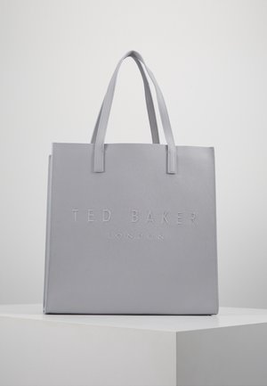 Sac fourre-tout gris Ted Baker London avec deux poignées, texture lisse et nom de la marque en relief à l'avant, posé sur un socle blanc.