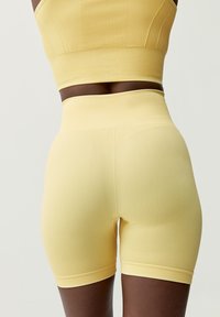 Geel geribbeld sport crop top en hooggeknoopte shorts, gemaakt van rekbaar materiaal, met een gladde textuur en een aansluitend ontwerp.