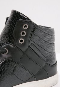 Svarta hög-top sneakers med texturerat reptilmönster, metalliska öglor och ett slätt läder överdrag; texturerade svarta detaljer på sidorna.