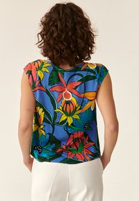 Bluse mit Blumenmuster auf blauer Hintergrund, mit kurzen Ärmeln und einem fließenden Design. Sie ist mit lebhaften orangen, gelben und grünen Blumen verziert.