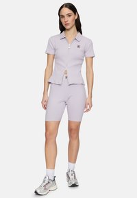 Lavendel ribgebreid set bestaande uit een rits polo-shirt en hoge shorts. Heeft een klein logo-opdruk op het shirt.