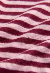 Tissu en tricot présentant des rayures alternées bordeaux et rose clair, avec une texture douce et un aspect drapé délicat.