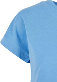 T-shirt en coton bleu clair à manches courtes, avec un col rond et une texture lisse. Aucun motif ni détail métallique visible.