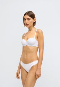 Soutien-gorge rembourré blanc avec bretelles réglables et culotte assortie bordée de dentelle, offrant une texture lisse et un design moulé.