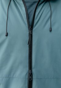 Svetlo modra jakna z zadrgo spredaj, črnimi detajli, nastavljivimi vrvicami in gladko, mat teksturo.