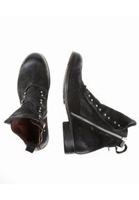 Bottines en daim noir avec une fermeture éclair latérale, des clous argentés le long de l'ouverture, et un petit talon empilé.