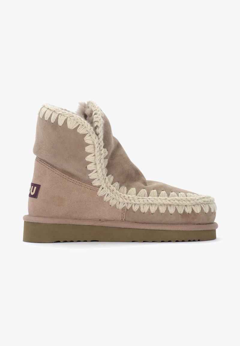 Botte cheville en suède beige avec un bord tressé crème texturé le long de l'ouverture et une semelle en caoutchouc. Doublure douce visible en haut.
