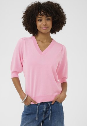 Suéter rosa de cuello en v con mangas cortas abullonadas, textura suave, dobladillo acanalado, combinado con vaqueros azules informales, con una pulsera redonda plateada.