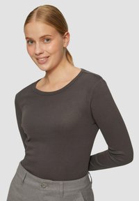 Langdurige, aansluitende top in donkergrijze katoen, met een ronde halslijn en subtiele textuur. Gekoppeld aan hoog-waist lichtgrijze broeken.