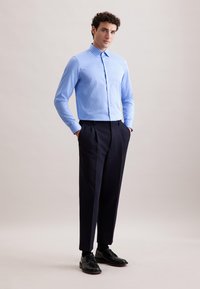 Camicia a righe blu chiaro con colletto, abbinata a pantaloni eleganti scuri. L'outfit include scarpe nere stringate ed ha una texture liscia.