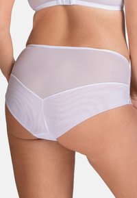 Hvide mesh trusser med en glat elastisk talje. Har et semi-gennemsigtigt bagpanel og en solid front, der fremhæver et minimalistisk design.