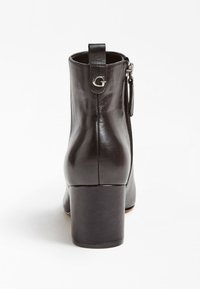 Černá kožená kotníková bota s blokovým podpatkem, zadním poutkem se znakem "G" z kovu a bočním zipem na bílém pozadí.