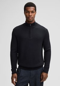 Zwarte gebreide trui met rits aan de hals, voorzien van een textuurpatroon, ribgebreide mouwen en onderrand, met een korte rits voor een moderne, casual uitstraling.