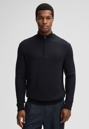 Black knit zip-neck sweater with a textured pattern, ribbed cuffs and hem, featuring a short zipper for a modern, casual design.